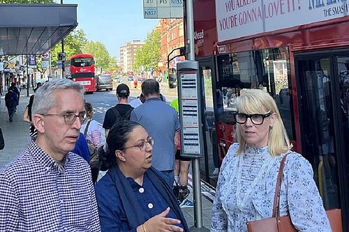 Photo of two men and a woman by a bus stop